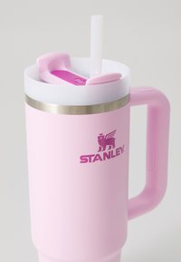 Pink stainless steel tumbler with a white lid, straw, and purple accents. Features a handle and the "STANLEY" logo. Smooth matte texture.