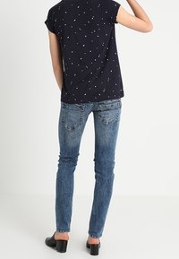Mörkblå kortärmad topp med vita prickar, kombinerad med ljusblå slim fit-jeans med två bakfickor och en urtvättad finish.