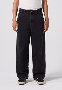 Pantalon en denim noir à coupe ample, doté d'une fermeture à boutons, de cinq poches et de coutures contrastées. Le tissu est robuste avec une texture lisse.