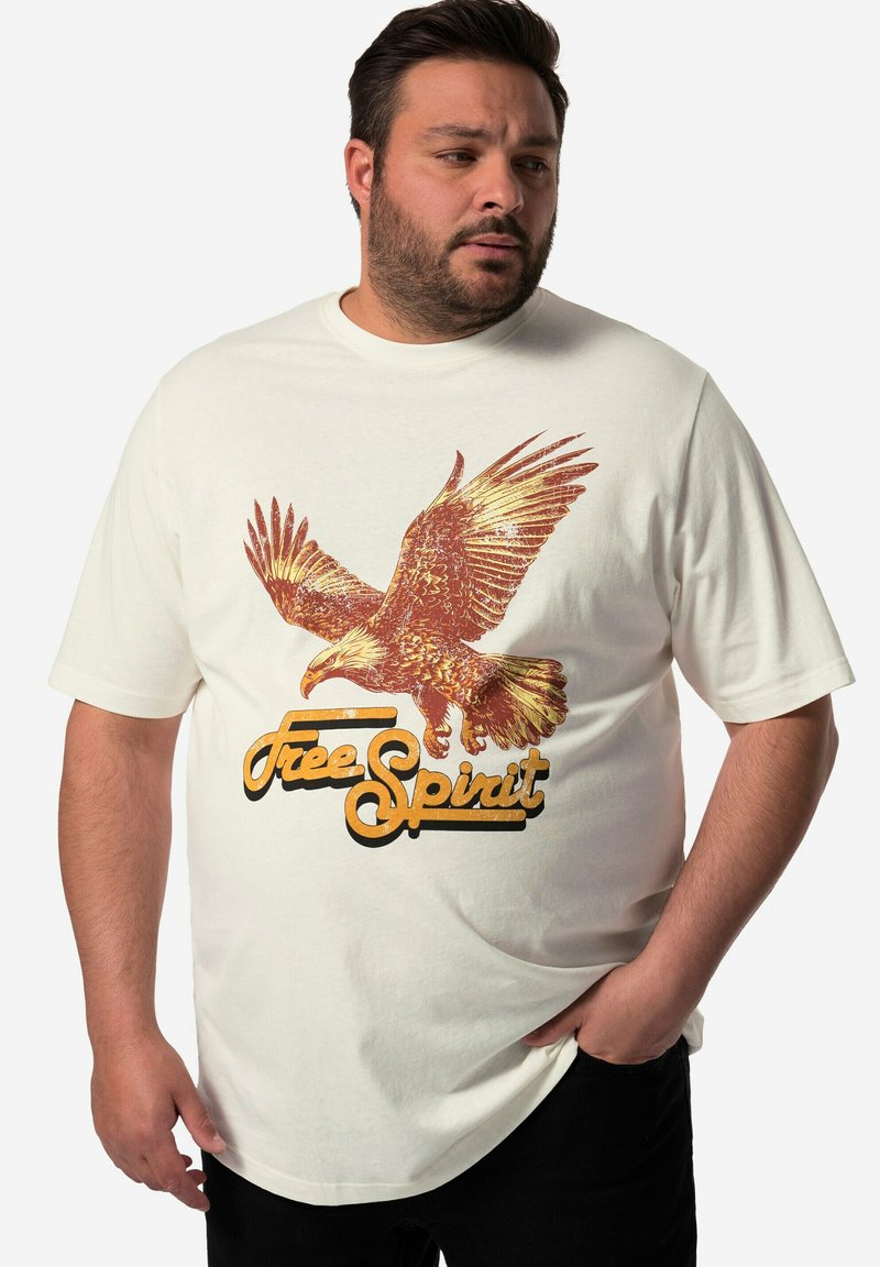 Camiseta de algodón blanca con un gráfico de águila dorada y el texto "Free Spirit" en negro y dorado. Cuello redondo y corte relajado.