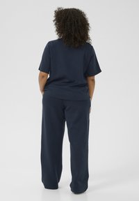 Navy blue relaxed-fit short-sleeve top and matching wide-leg pants, featuring a smooth texture and minimalistic design.