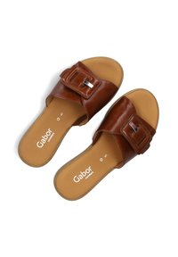 Brown leather slide sandals with a wide strap featuring a square buckle. Smooth texture, cushioned footbed, and a simple design.