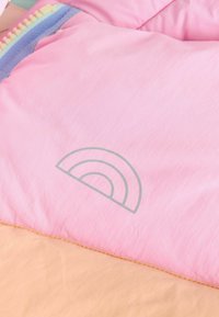 Tela de chaqueta acolchada rosa con una textura suave. Presenta un gráfico de arcoíris gris y un dobladillo de color durazno suave con costuras visibles.
