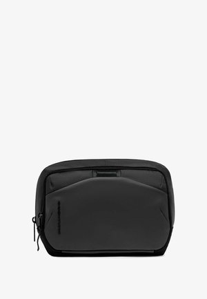 Zwart etui met ritssluiting, voorzien van een getextureerde nylon bovenkant en een gladde matte voorkant. Compact rechthoekig ontwerp met een slank profiel en subtiele branding.