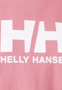 Texto del logo blanco de Helly Hansen sobre fondo de tela rosa, mostrando parte del nombre de la marca en letras negritas.