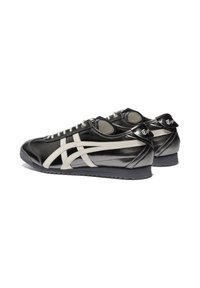 Scarpe sportive bianco e nero con tomaia in pelle lucida, caratterizzate da una distintiva striscia bianca del logo e suola nera texturizzata.
