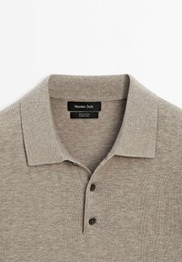 Polo en coton marron clair avec col et deux boutons, étiqueté Massimo Dutti, fabriqué en Chine.