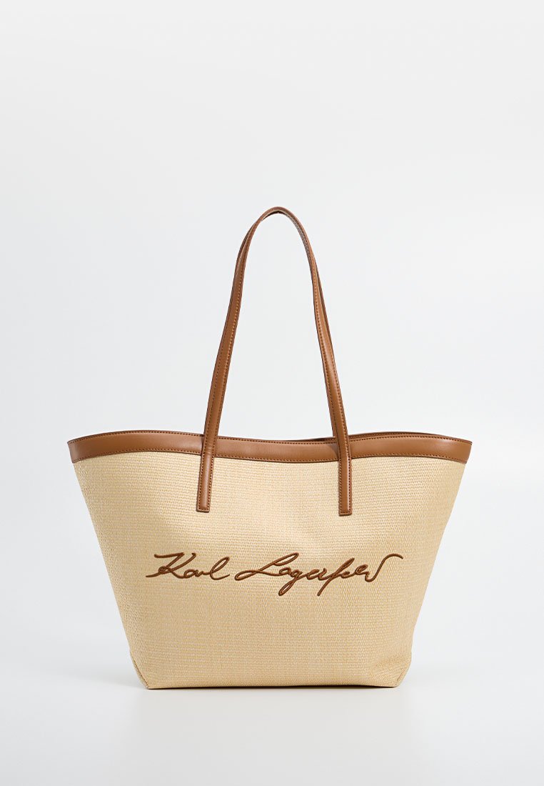 Beige gewebte Tasche mit braunen Lederakzenten und -griffen. Auf der Vorderseite befindet sich ein geschwungenes Logo in Braun. Robustes und geräumiges Design.