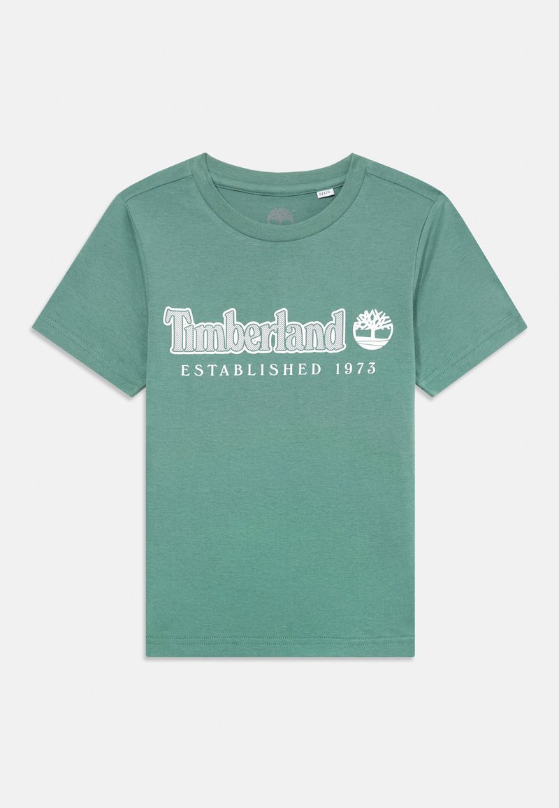 Grønn bomull t-skjorte med korte ermer, med teksten "Timberland" og "Etablert 1973" i hvit tekst, rund hals, glatt tekstur.
