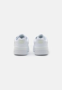Hvite lær sneakers med en glatt tekstur, rund form, og en lys grønn aksent på hælen. Gummisåle og minimale designelementer.