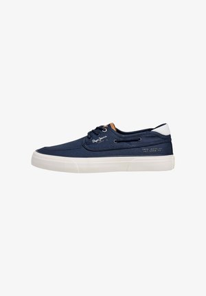 Sneaker in tela blu navy con suola in gomma bianca, con dettagli in pelle marrone, occhielli in metallo e logo stampato sul lato.