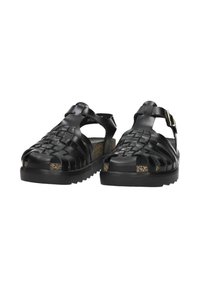 Black woven sandals with an open toe design, cork-finished insole, adjustable strap, and textured rubber sole for grip.