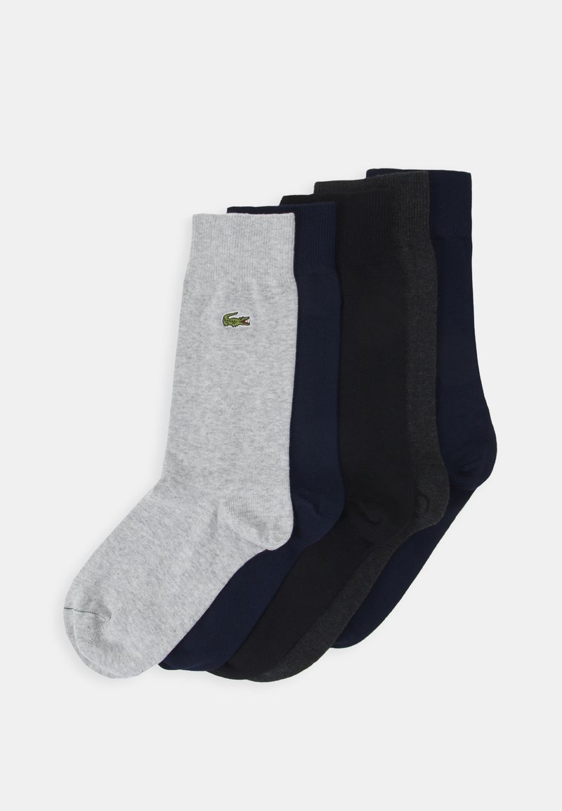 Cinco pares de calcetines en diferentes tonalidades de gris y azul marino, con un pequeño logo verde de Lacoste en el calcetín gris, fabricados con material suave.