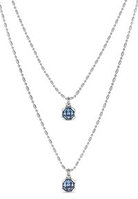 Collier en chaîne argentée à deux couches ; la couche inférieure présente un pendentif en pierre précieuse bleue octogonale, affichant des détails de taille et de sertissage complexes.