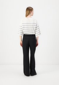 Lightweight, striped sweater in white and grey; paired with black, wide-leg pants featuring a belted waist and side pockets.