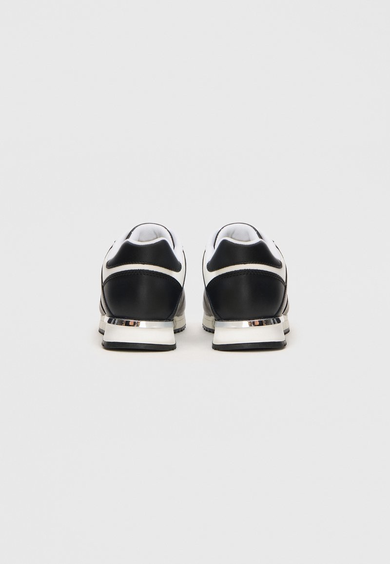 Zapatillas en blanco y negro con un diseño elegante, parte superior de piel, acentos en contraste y un detalle metálico en el talón. Suela texturizada.