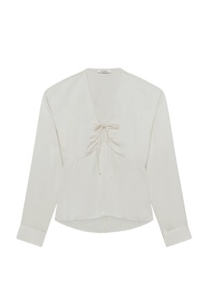 Blouse blanche à manches longues avec un profond col en V, détail noué à l'avant, tissu froncé sur la poitrine et ourlet légèrement incurvé.