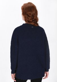 Navy-blaues oversized Sweatshirt mit strukturiertem Strick, überschnittenen Schultern, gerippten Bündchen und rundem Halsausschnitt. Mit einem Logopatch auf der Rückseite.