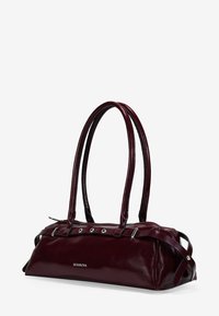 Bolso de cuero burdeos con dos asas largas, acentos de hardware plateado y forma rectangular. Presenta una placa de marca en la parte frontal.