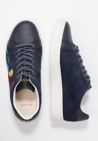 Navy leather and suede sneakers featuring embroidered colorful floral design, contrasting light sole, and flat laces in matching color.