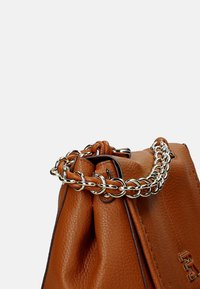 Borsa in pelle marrone con apertura a coulisse, dotata di manico in catena argentata e superficie leggermente testurizzata. Il logo del brand è visibile sul lato.