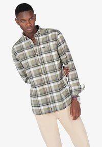 Camisa de botones con un patrón de cuadro en colores verde, blanco y marino. Cuenta con mangas largas y un collar, hecha de tela ligera.