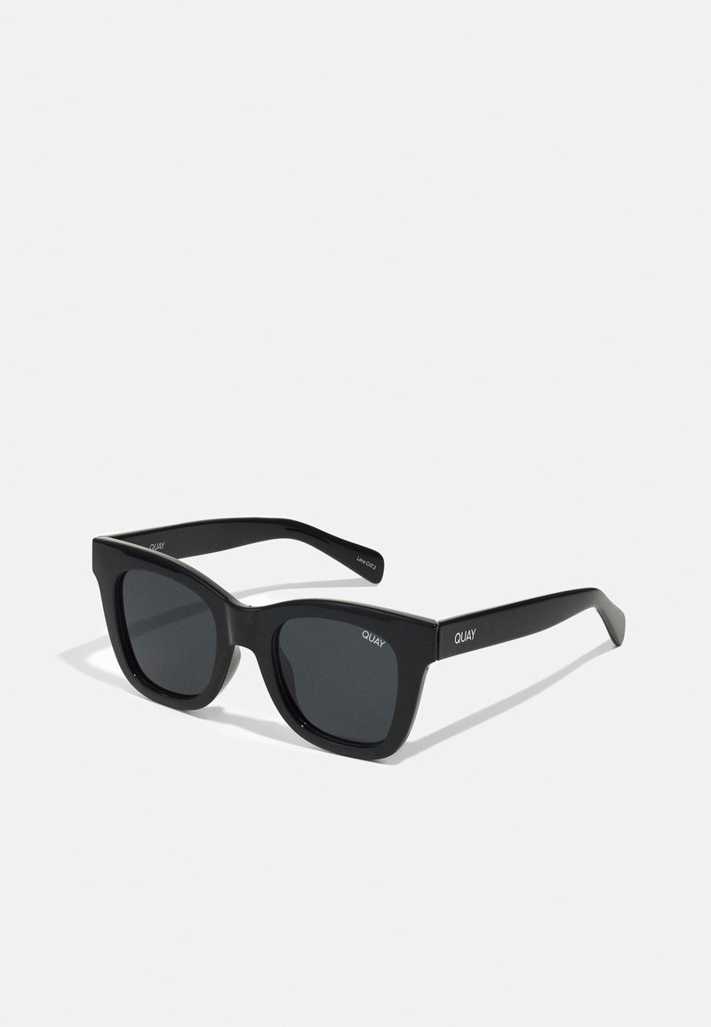 Black rectangular sunglasses with a smooth plastic frame and dark lenses. "QUAY" logo on the side in white. Minimalist design.