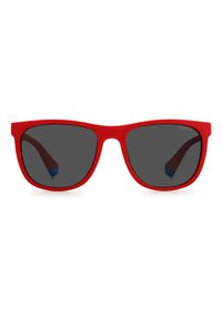 Lunettes de soleil en plastique rouge avec des verres foncés. Forme carrée, branches flexibles avec un accent bleu à l'intérieur. Texture lisse, design léger.