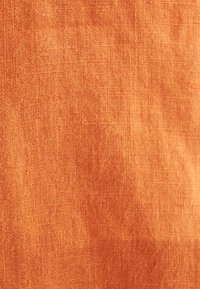 Tessuto testurizzato in calde tonalità di arancione, caratterizzato da una fine trama con sottili variazioni, ideale per rivestimenti o design di abbigliamento.