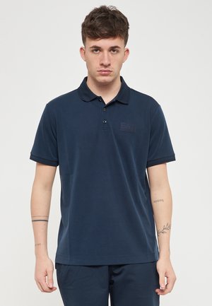 Polo shirt blu navy in tessuto morbido, con colletto, maniche corte e un discreto patch del logo sul lato sinistro in alto.
