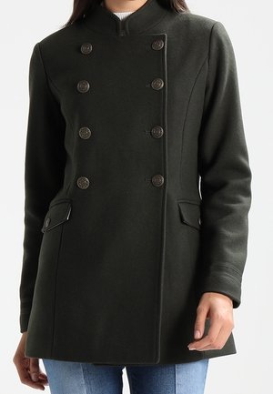 Tumma vihreä takki, jossa on korkea kaulus, kaksirivinen nappisulku, kaksi etutaskua ja teksturoitu villakangas.