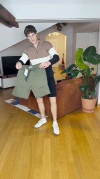 Grüne Shorts mit einem elastischen Taillenbund, zwei Seitentaschen und einem angebrachten Etikett. Glatter Stoff, knielanger Schnitt und lässiges Design.