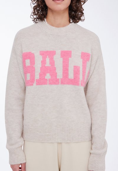 Lysbeige strikket sweater med iøjnefaldende pink "BALI" bogstaver, ribbet kant ved ærmerne og forneden samt blød tekstur. Enkel rund halsudskæring.