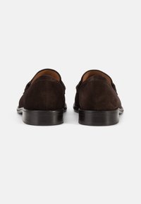 Dark brown suede shoes with a smooth texture, low stacked heels, and a classic design. The back features curved edges and clean stitching.
