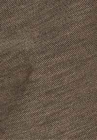 Närbild av grovt brunt tyg med vriden diagonalt vävsmönster som skapar en strukturerad yta.