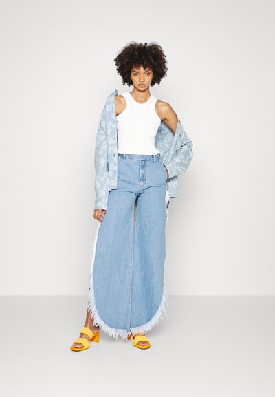 Light blue denim jacket with flower pattern, white tank top, wide light blue jeans with fringed hem, and yellow heeled sandals.