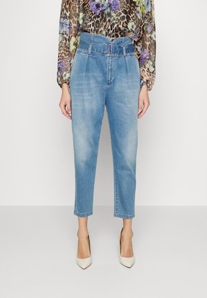 Hellblaue, hoch taillierte, verjüngte Jeans mit Falten und passendem Gürtel, kombiniert mit einer Bluse mit floralem Leopardenmuster und weißen spitzen Absätzen.