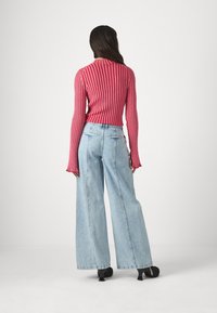 Rød stripete genser med lange ermer, satt sammen med lyseblå vide denimjeans. Antrekket har innsnevret midje og klokkeformet kant.