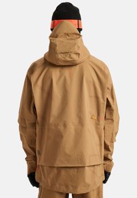 Brązoowa wodoodporna kurtka z kapturem, charakteryzująca się teksturowanym wykończeniem, kontrastującymi pomarańczowymi akcentami oraz logo. Zawiera przestronną konstrukcję pleców.