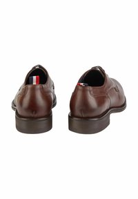 Braune Leder Schuhe mit glatter Textur, runder Spitze und kontrastierender dunkler Sohle. Verfügt über ein farbenfrohes Etikett an der Ferse.