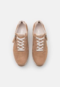 Suede sneakers in light brown with white laces, zipper accent, rounded toe, and padded collar. Features logo on insole.