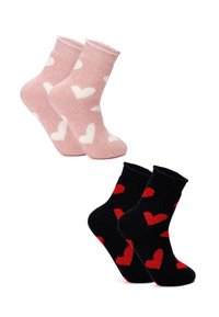 Two pairs of cozy socks: one light pink with white heart patterns, and one black featuring red heart designs. Both have ribbed texture.