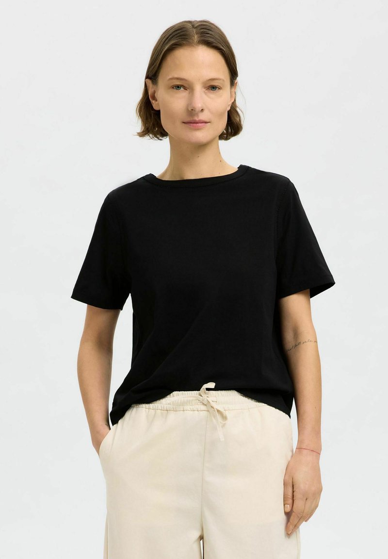 Svart bomulls t-shirt med rund halsringning och korta ärmar, kombinerad med beige byxor med dragsko. Enkelt mönster, mjuk textur.