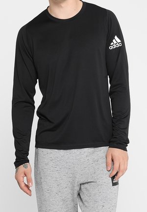 Schwarz langärmliges Sportshirt aus glattem, leichtem Stoff. Mit einem weißen Adidas-Logo auf dem linken Ärmel.