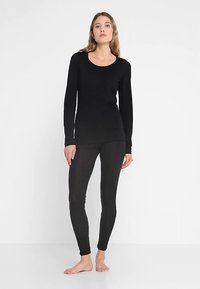 Top nero a maniche lunghe e leggings realizzati in tessuto morbido, con scollo tondo e vestibilità attillata. Design minimalista senza motivi o accenti.