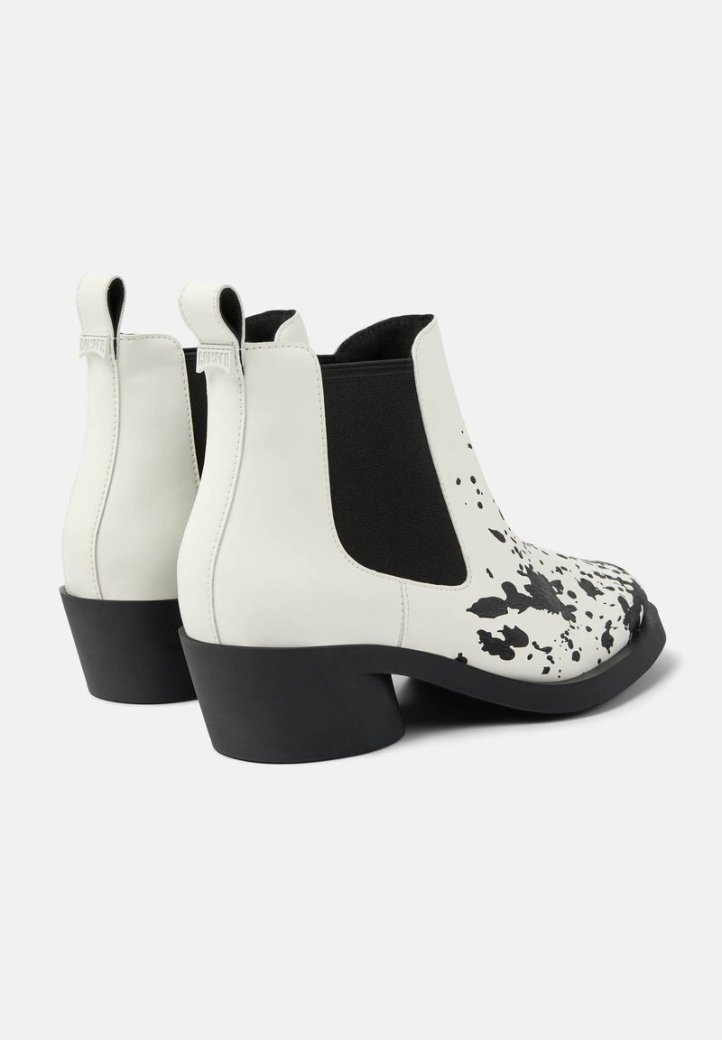 Weiße Lederstiefeletten mit schwarz-spritzendem Design, elastischen Seitenpaneelen und einem klobigen schwarzen Absatz. Glatte Textur mit Zugschlaufen.