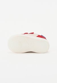 Red and pink canvas sneaker with a rubber sole, featuring contrasting blue accents and a textured outsole for grip.