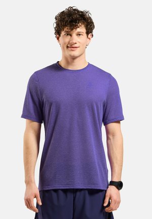 Paarse sport T-shirt met korte mouwen, gemaakt van textuurstof die vocht afvoert. Heeft een ronde hals en zit iets losjes aan de zoom.
