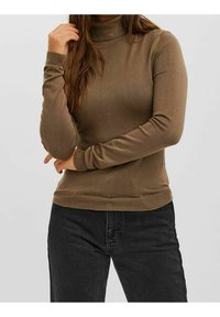 Brauner Rollkragenpullover mit geripptem Kragen und Bündchen, aus einem weichen Stoff gefertigt. Er hat ein tailliertes Design und wird mit dunklen Jeans getragen.