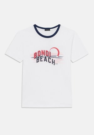 T-shirt en coton blanc avec un col rond côtelé bleu marine. Présente un imprimé graphique de "BONDIE BEACH" en rouge et noir, avec un soleil stylisé et des vagues.